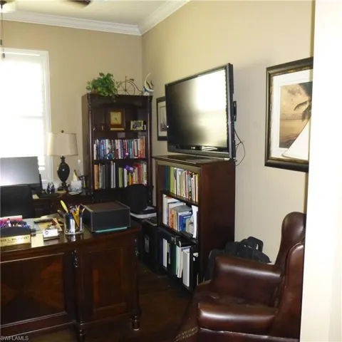 Home office featuring dark wood-type flooring and ornamental molding