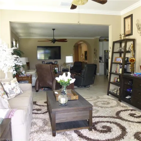 Tiled living room with crown molding and ceiling fan