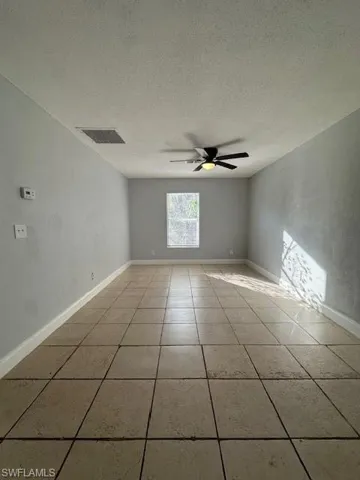 Unfurnished room featuring a textured ceiling, a ceiling fan, and light tile patterned floors