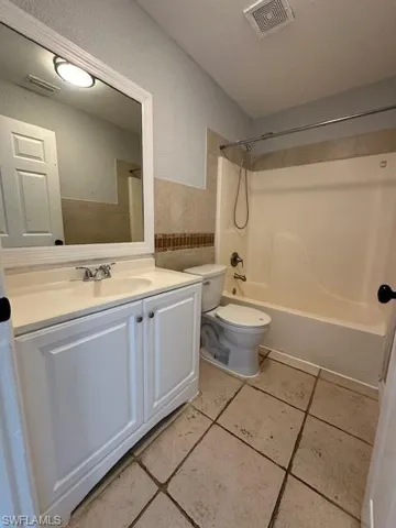 Full bath with vanity, bathing tub / shower combination, a textured wall, a textured ceiling, and light tile patterned flooring