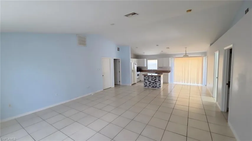 Spacious open-concept living area featuring light blue walls and white tile flooring