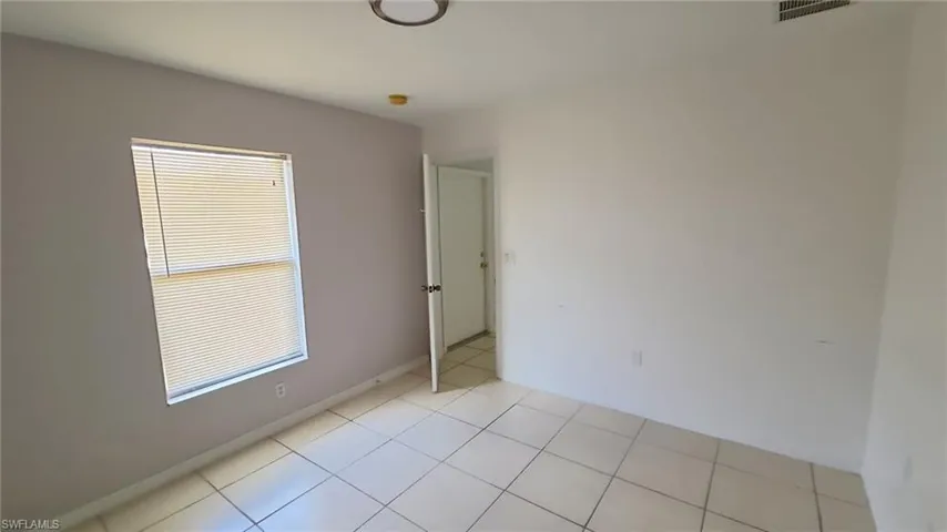 Room featuring ceramic tile flooring, a window with horizontal blinds, and a neutral color palette