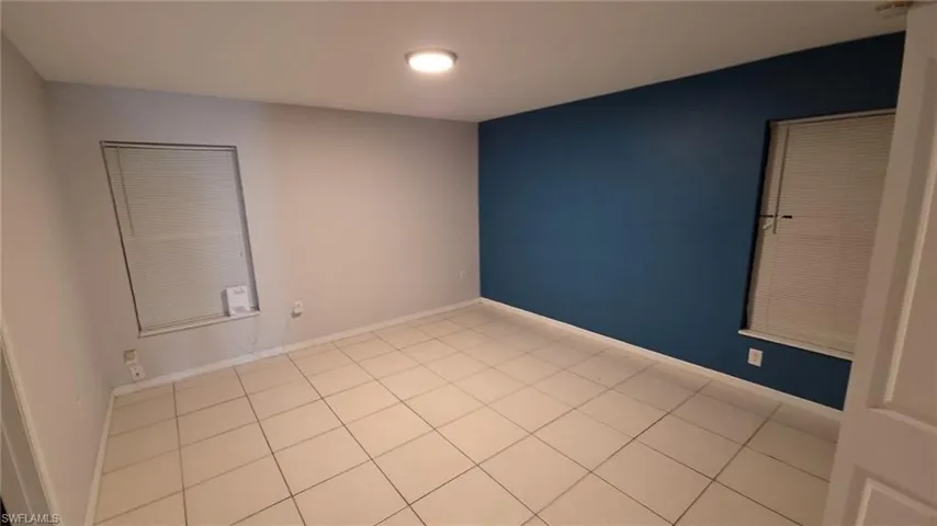 Spacious room featuring tile flooring, a recessed ceiling light, and a prominent accent wall in a deep blue hue