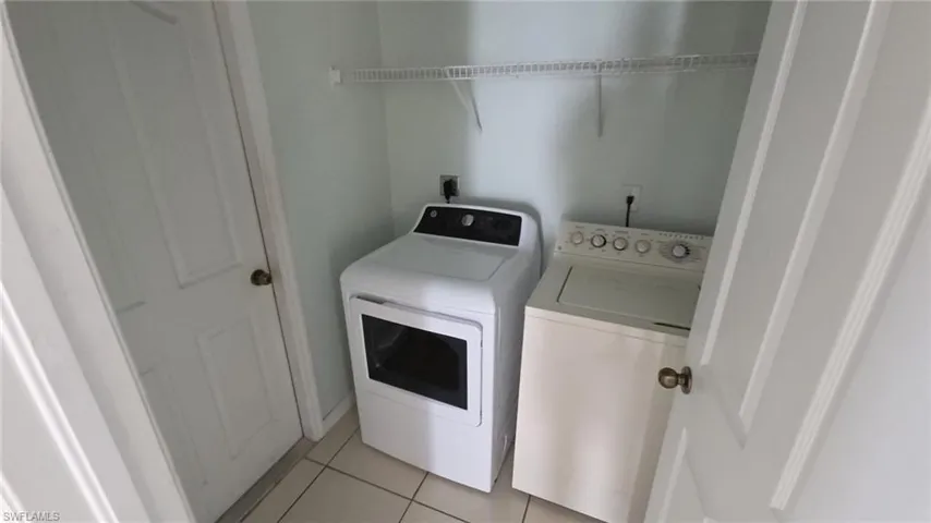 Utility closet featuring light blue walls, a white wire shelf, and tile flooring