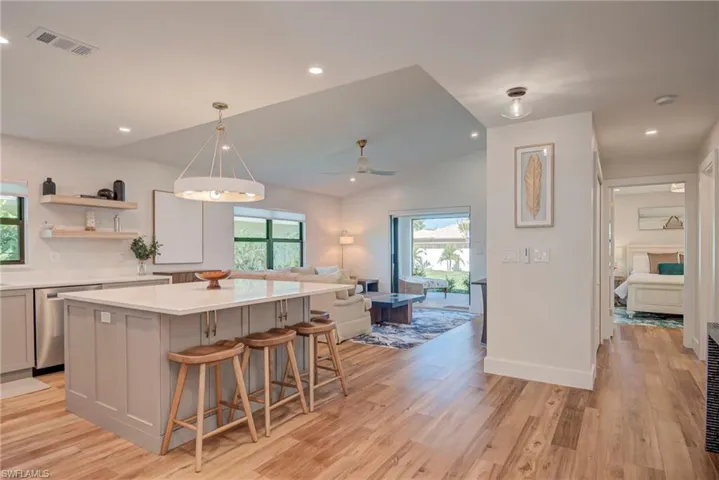 Kitchen with gray cabinetry, a kitchen breakfast bar, hanging light fixtures, light wood finished floors, and recessed lighting