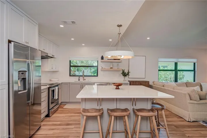 Kitchen with stainless steel appliances, a center island, hanging light fixtures, a breakfast bar, and open floor plan