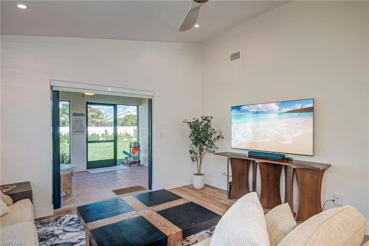 Living area featuring lofted ceiling, wood finished floors, recessed lighting, and a ceiling fan