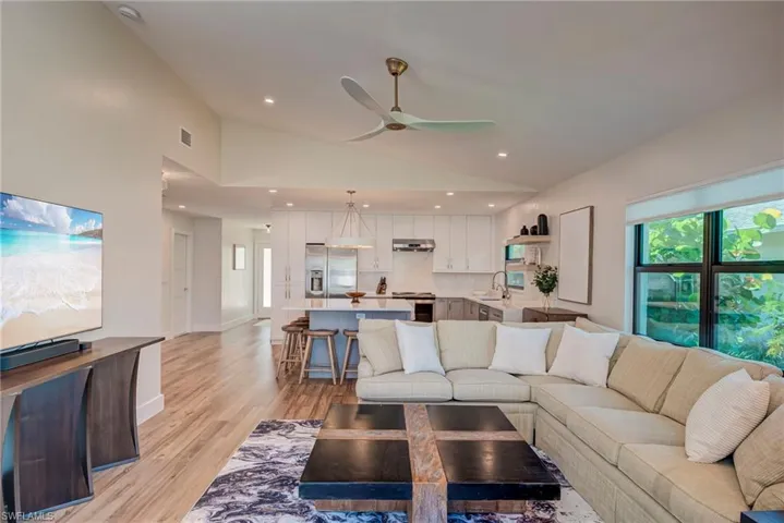 Living room with light wood-style flooring, recessed lighting, ceiling fan, and high vaulted ceiling