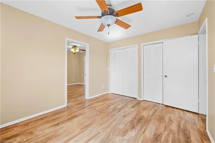 Unfurnished bedroom featuring two closets, light wood-type flooring, and a ceiling fan
