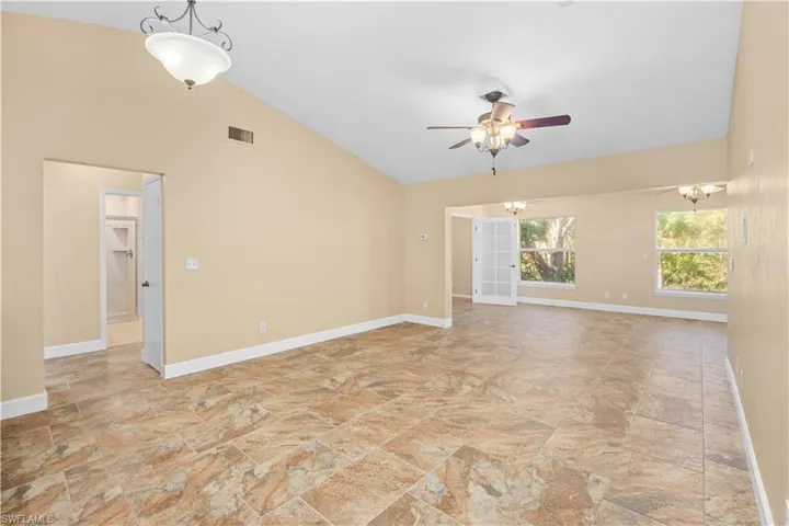 Unfurnished room featuring lofted ceiling, ceiling fan, and suspended lighting