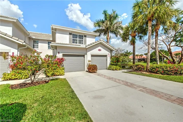 Traditional-style home with stucco siding, concrete driveway, an attached garage, and a front lawn