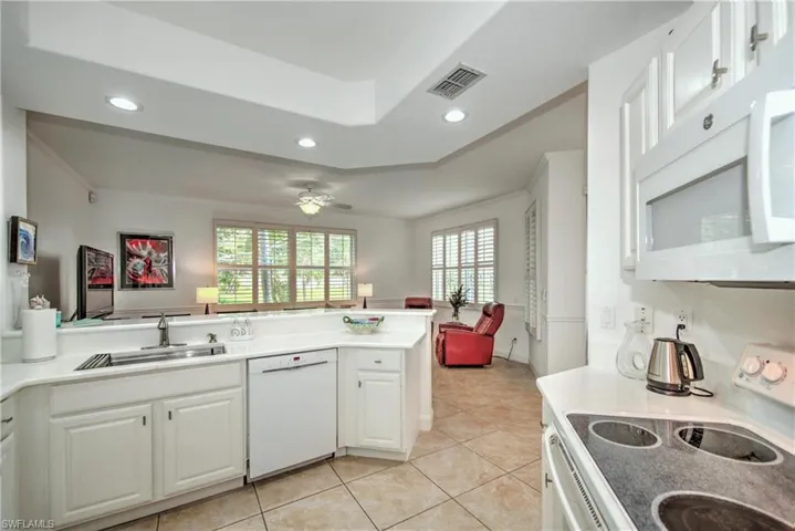 Kitchen with white appliances, white cabinets, open floor plan, light countertops, and light tile patterned floors