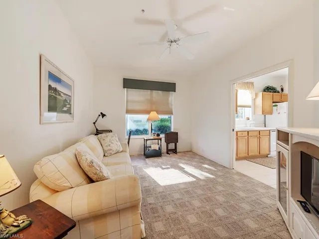 Living room with ceiling fan, light colored carpet, and plenty of natural light