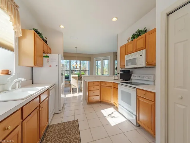 Kitchen with light tile patterned floors, an inviting chandelier, sink, decorative light fixtures, and white appliances
