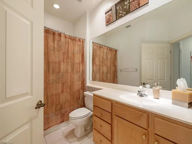 Bathroom featuring toilet, curtained shower, vanity, and tile patterned floors