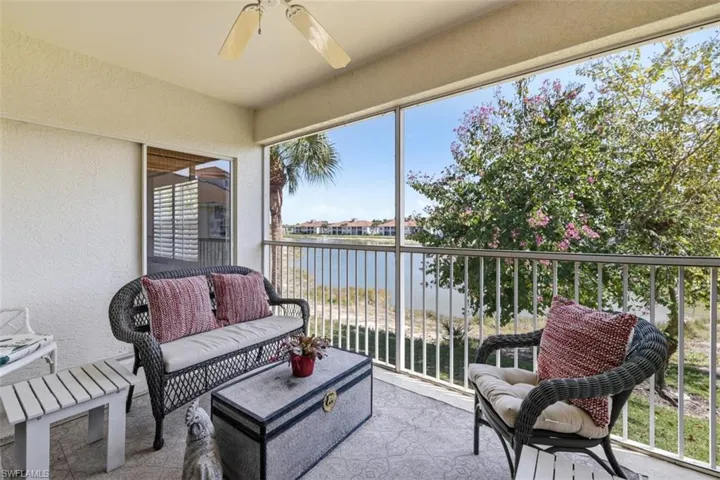 Sunroom featuring a ceiling fan, a balcony, and a water view