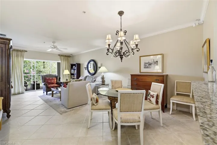 Dining room with crown molding, a chandelier, a ceiling fan, and light tile patterned flooring