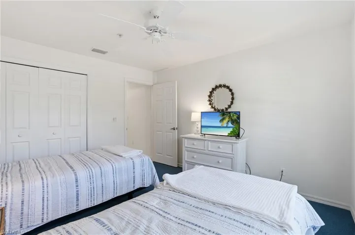 Bedroom featuring dark colored carpet, a ceiling fan, and a closet