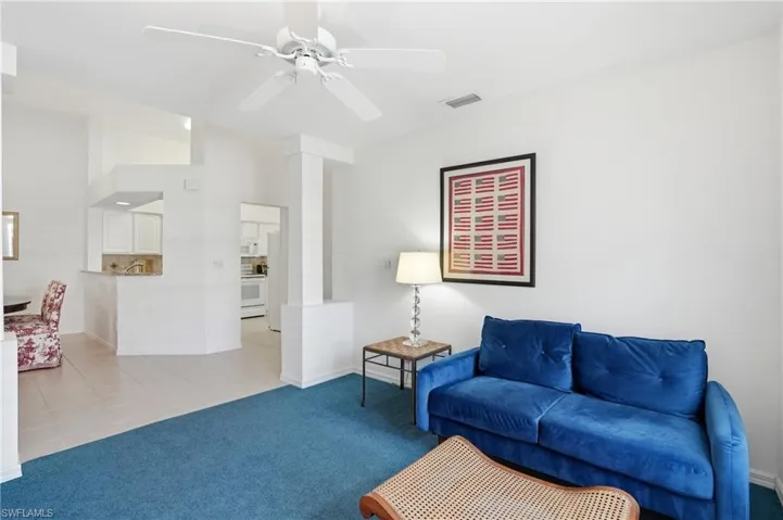 Living area featuring light colored carpet, light tile patterned flooring, and a ceiling fan