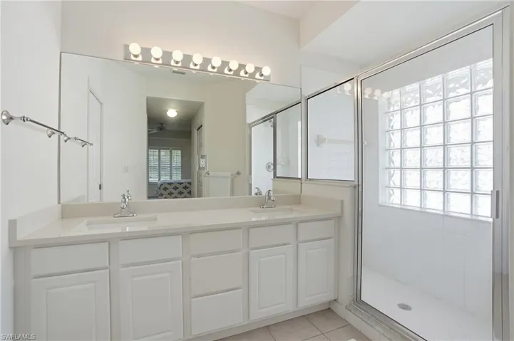 Bathroom featuring double vanity, ensuite bathroom, a shower stall, light tile patterned floors, and a ceiling fan