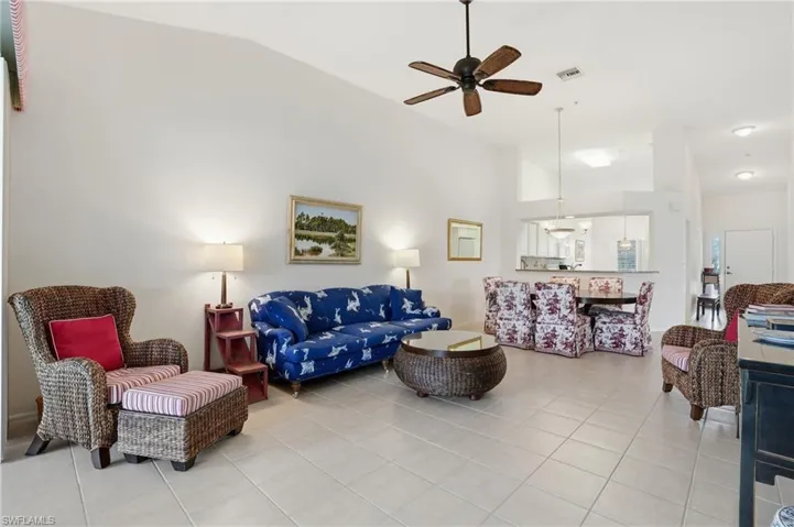 Living room featuring vaulted ceiling, a ceiling fan, and light tile patterned floors