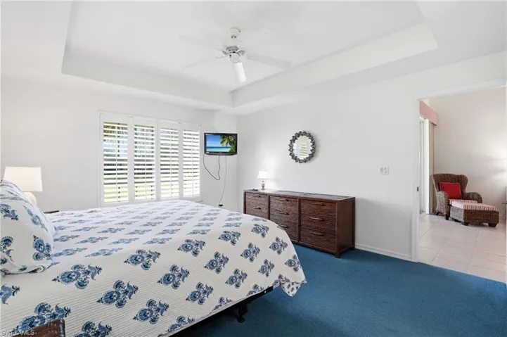 Bedroom with a tray ceiling, carpet flooring, and ceiling fan