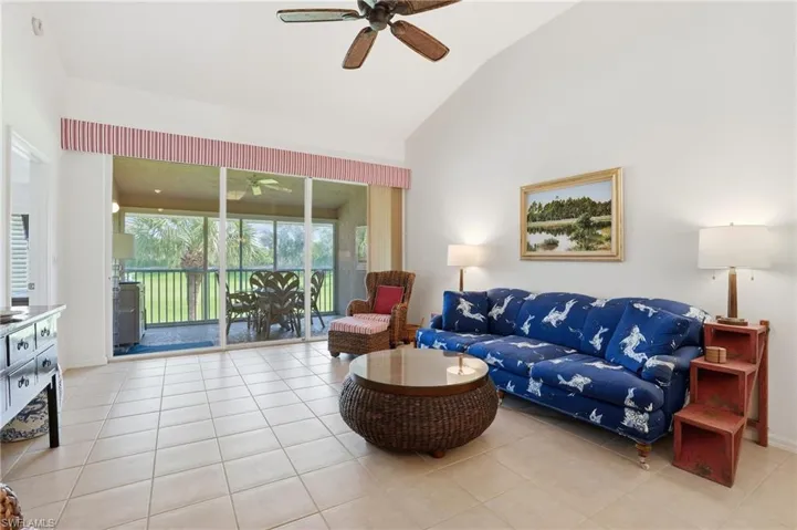 Living area featuring ceiling fan, lofted ceiling, a sunroom, and light tile patterned floors