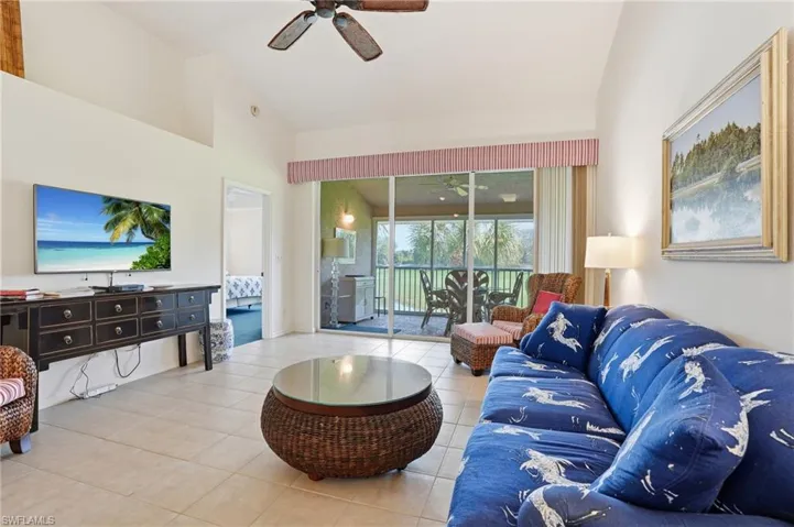 Living room with ceiling fan, a sunroom, lofted ceiling, and light tile patterned floors