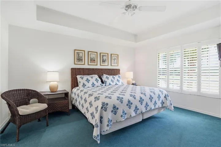 Carpeted bedroom featuring a tray ceiling and ceiling fan