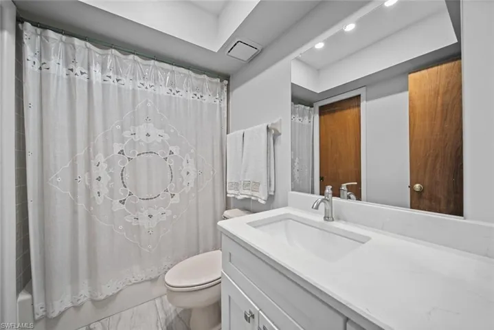 Bathroom featuring toilet, vanity, shower / bath combo, and recessed lighting