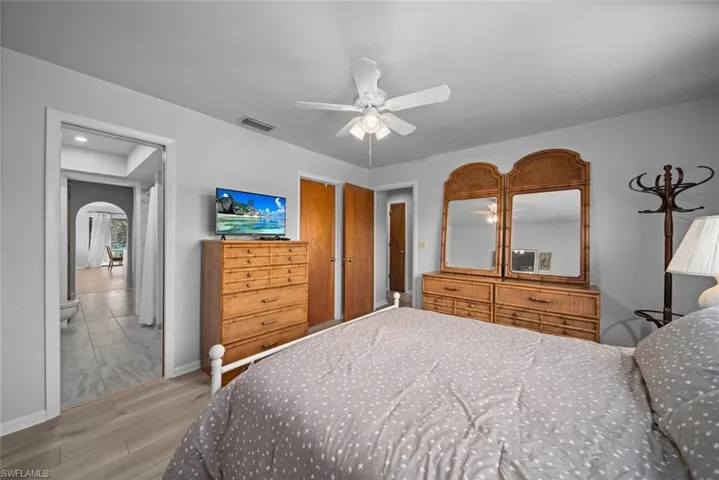 Bedroom featuring wood finished floors, arched walkways, baseboards, and ceiling fan