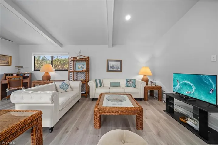 Living room with beam ceiling and light wood-style flooring