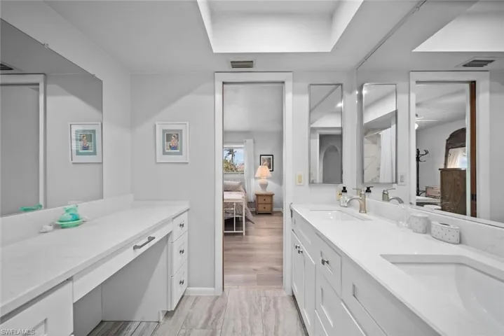 Full bathroom with ensuite bath, double vanity, and baseboards