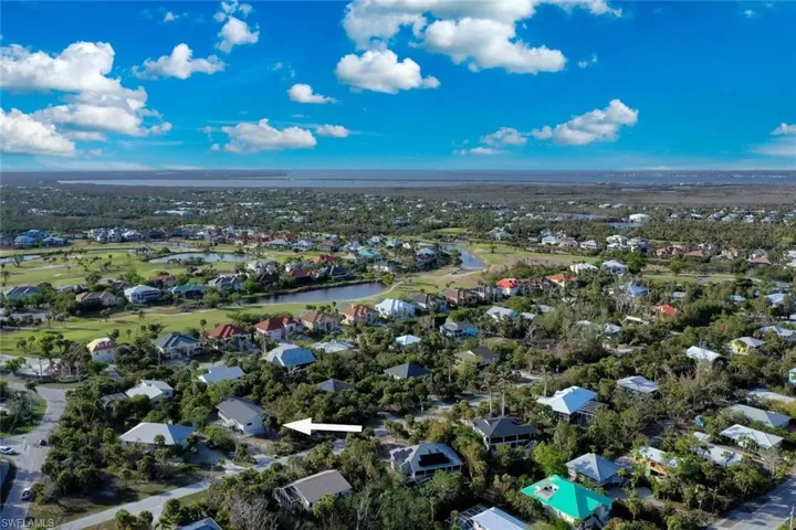 Aerial view of property and surrounding area featuring nearby suburban area, a nearby body of water, and a golf club