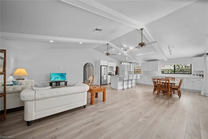 Living area with ceiling fan, light wood-style floors, and arched walkways