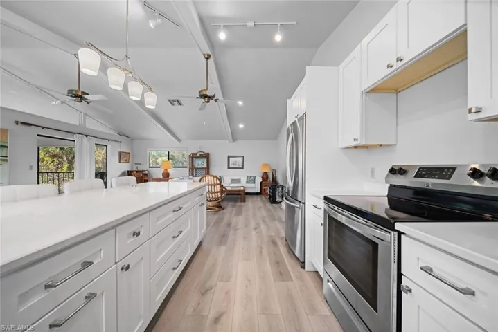Kitchen featuring appliances with stainless steel finishes, ceiling fan, lofted ceiling, open floor plan, and light countertops