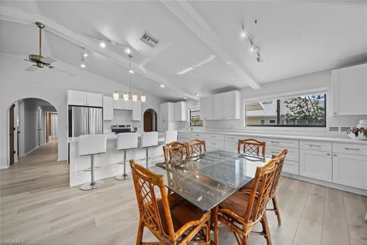 Dining space featuring arched walkways, light wood-style flooring, and plenty of natural light