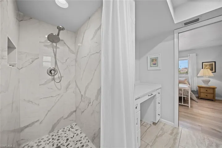 Full bath featuring a marble finish shower and connected bathroom