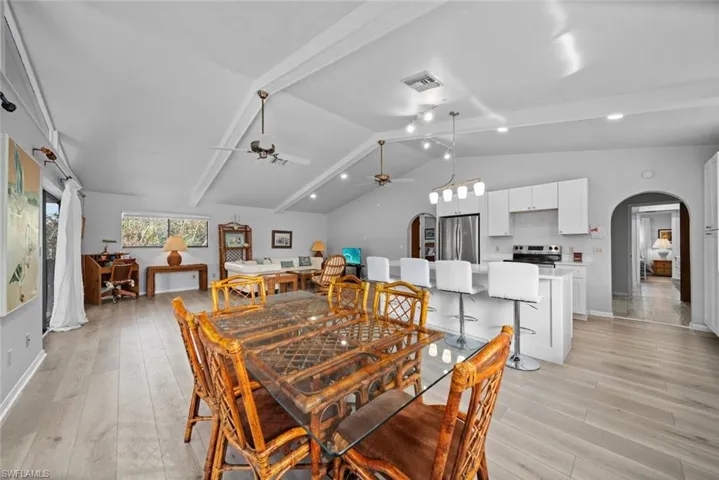 Dining space with arched walkways, a ceiling fan, light wood-style flooring, and baseboards