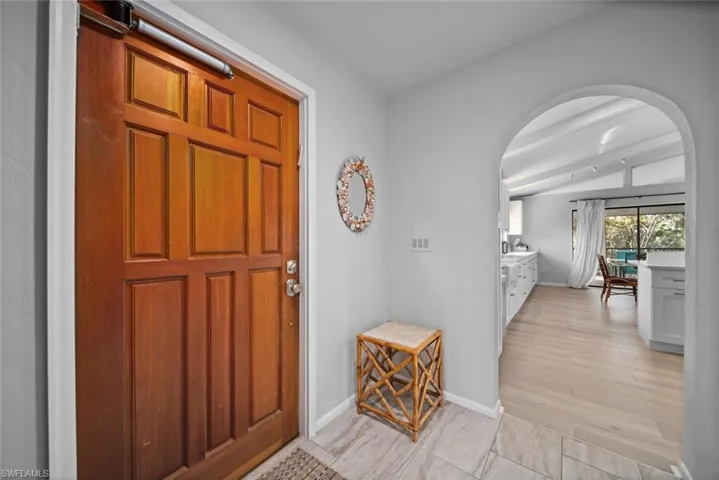 Foyer entrance with arched walkways, baseboards, and light wood-type flooring