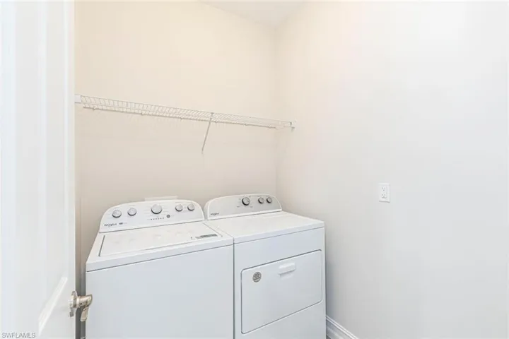 Washroom featuring independent washer and dryer and baseboards