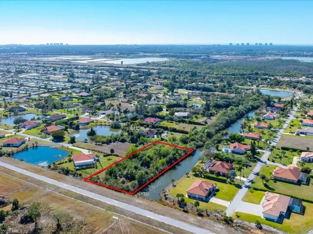 Aerial view of residential area featuring property boundaries highlighted and a large body of water