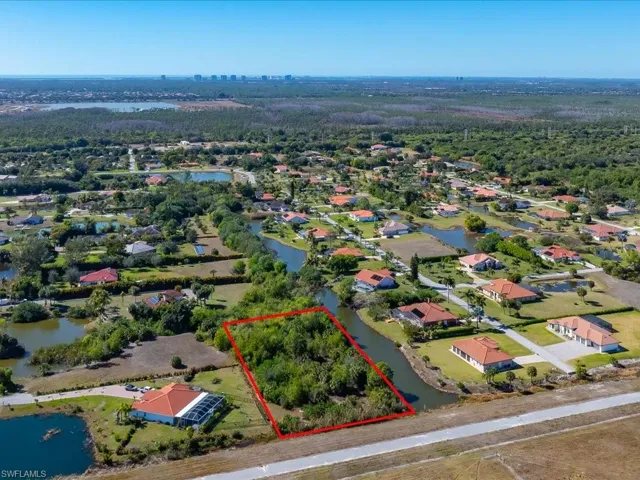 Aerial perspective of suburban area with a nearby body of water and property boundaries highlighted