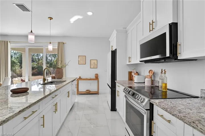 Kitchen featuring stainless steel electric range, white cabinetry, light stone countertops, hanging light fixtures, and light marble finish floors