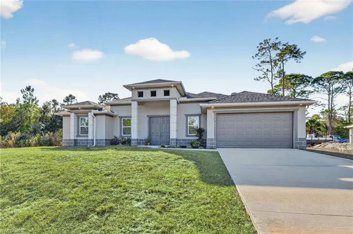 Prairie-style house featuring stucco siding, a front yard, concrete driveway, and an attached garage