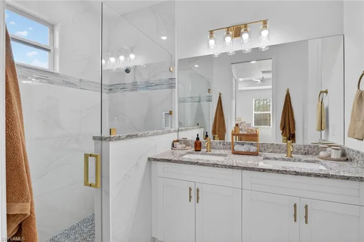 Bathroom featuring a marble finish shower and double vanity