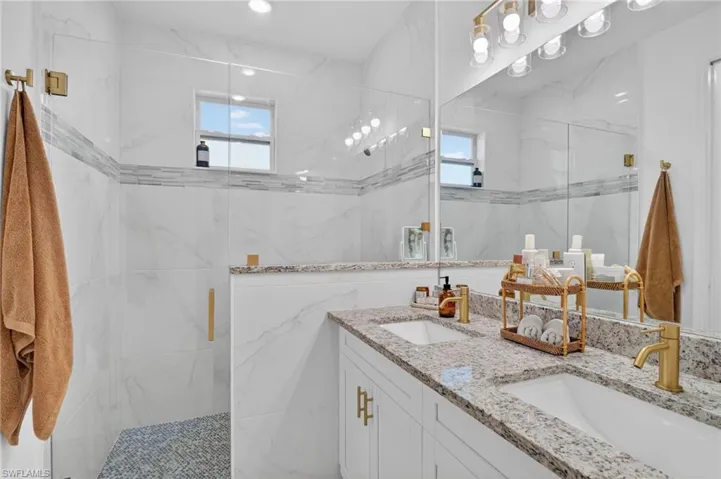Bathroom featuring a marble finish shower and double vanity