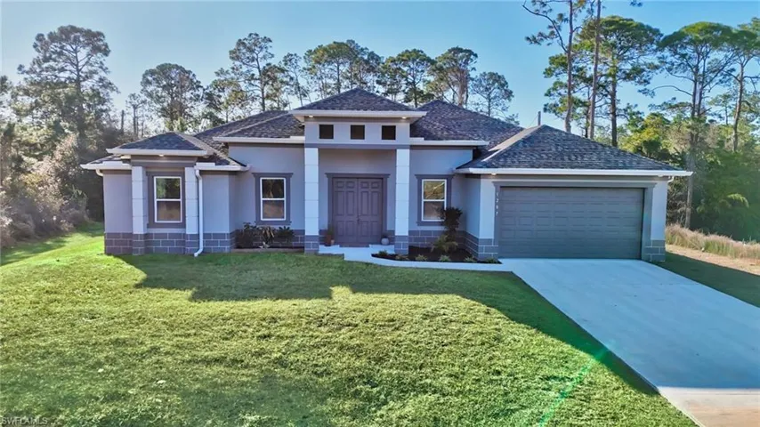 Prairie-style house featuring stucco siding, a front lawn, concrete driveway, a garage, and roof with shingles