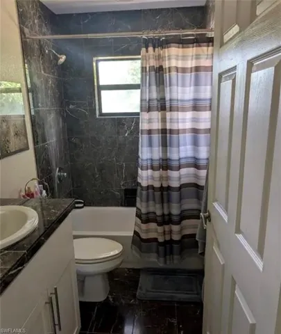 Bathroom featuring vanity and shower / bath combination with curtain