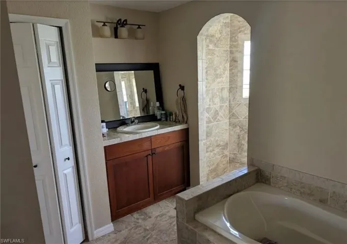 Bathroom with a garden tub, vanity, healthy amount of natural light, and a closet